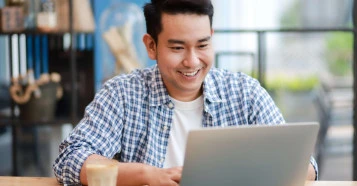 man smiling in casual wear on a laptop in an office