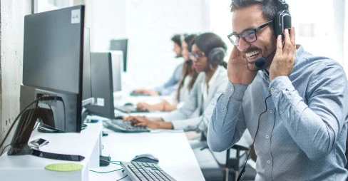 man in a suit with a headset laughing while taking call in call center