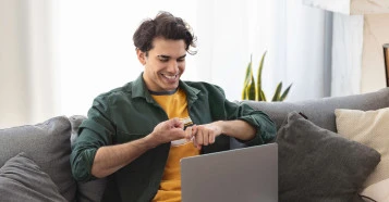 man on sofa smiling doing sign language on laptop