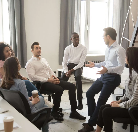 gathering of seven people wearing smart clothing talking in office