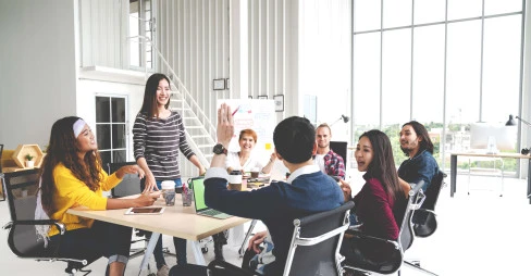 seven people smiling at meeting table with a man's arm raised