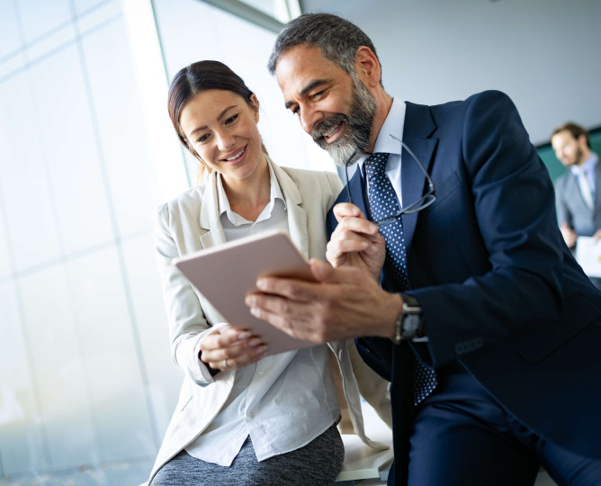 two people smiling while looking at tablet device
