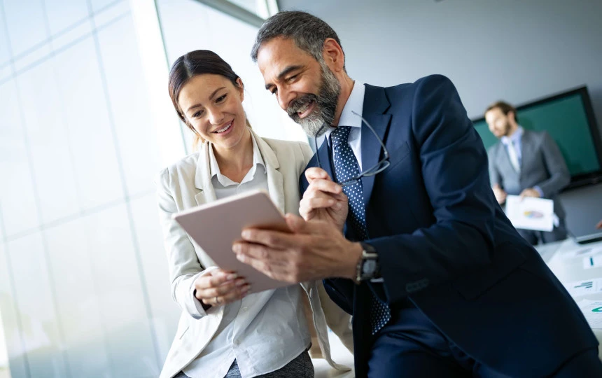 two people smiling while looking at tablet device