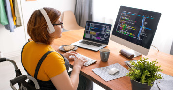 woman sitting in wheelchair with headphones on working on computer