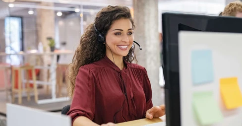 woman smiling sitting at desk with headset on