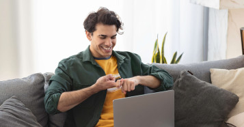 man on sofa smiling doing sign language on laptop